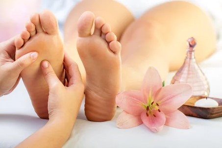 Geste de réflexologie sur un pied avec une fleur en décoration