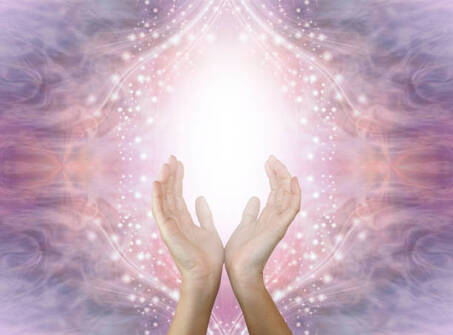 mains féminines ouvertes avec une lumière blanche entre les main sur un magnifique fond de champ d'énergie étincelant en dégradé de rose violet pêche